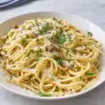 Sizzling spaghetti with ground beef, fresh herbs, and grated Parmesan cheese in white bowl