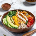 Southwestern Buddha Bowl with brown rice, beans, corn, avocado, lime wedges, spinach and yogurt dressing