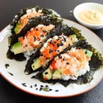 Homemade sushi tacos made with crispy nori shells filled with sushi rice, fresh salmon, avocado slices, and topped with black sesame seeds.