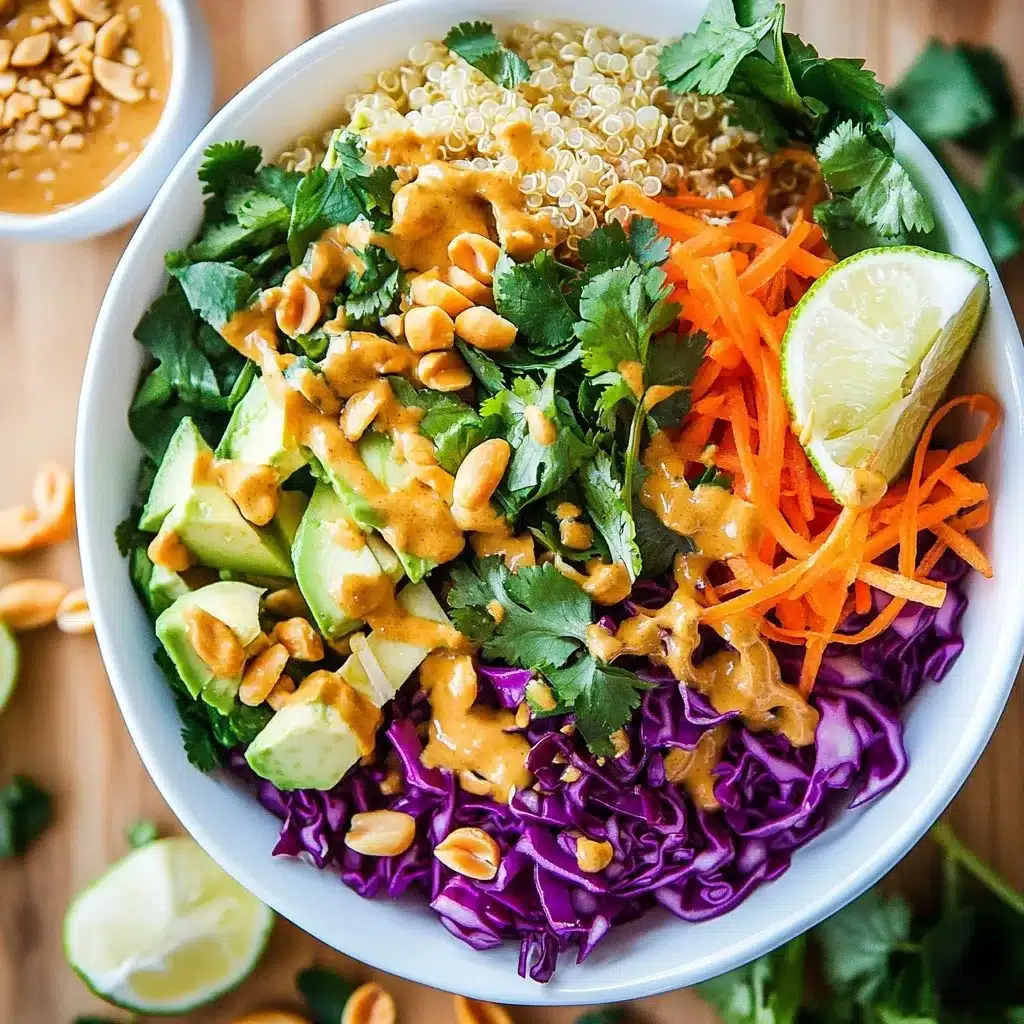 Thai Peanut Buddha Bowl with quinoa base, fresh vegetables, peanut sauce, cilantro and lime wedge served in a white bowl