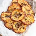 Golden crispy cottage cheese chips with black sesame seeds and sea salt on parchment paper