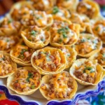 Crispy tortilla taco cups filled with seasoned meat and melted cheese garnished with fresh herbs on a blue-edged serving dish