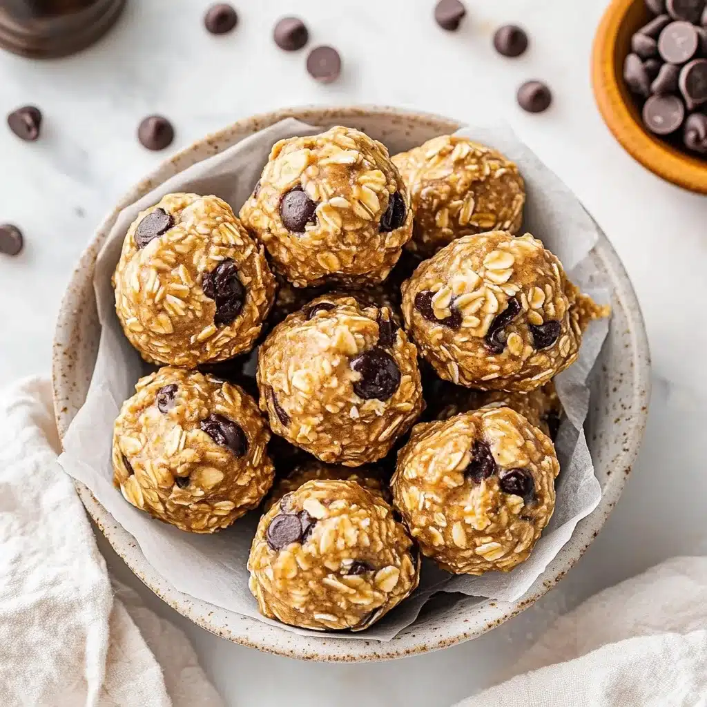 Freshly made peanut butter energy bites with chocolate chips arranged in a speckled ceramic bowl lined with parchment paper