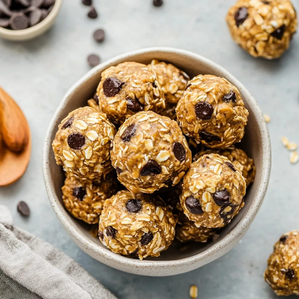 Peanut butter energy balls with visible oats and chocolate chips stacked in a neutral-colored bowl