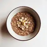 Nutty Mocha Crunch Overnight Oats topped with sliced almonds and chocolate chips in white bowl with brown rim