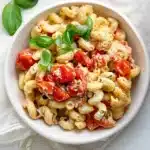 Individual serving of TikTok baked feta pasta in white bowl with roasted tomatoes and fresh basil
