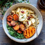 Autumn Harvest Grain Bowl with roasted sweet potatoes, quinoa, fresh apple slices, kale, and dried cranberries in a rustic ceramic bowl.