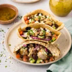 Close-up view of Mediterranean pita pocket filling with chicken, vegetables, feta cheese, and olive oil dressing
