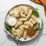 Cheese wrapped pickles served on elegant white platter with ranch and mustard dipping sauces for party appetizer presentation
