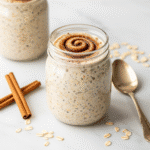 Cinnamon roll overnight oats in mason jar with cinnamon swirl on marble surface - healthy make-ahead breakfast recipe