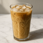Iced tahini coffee served in a glass with sesame swirls