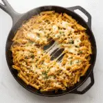 One-pan French onion pasta in cast iron skillet with golden caramelized onions and melted gruyere cheese