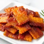Bacon crackers pig candy bites with caramelized brown sugar coating on white ceramic plate
