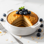Baked oats that taste like cake - golden fluffy texture in white ramekin with fresh berries