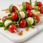 Elegant Caprese skewers with fresh mozzarella, cherry tomatoes, and basil on marble board - CrennRecipes.com premium appetizer