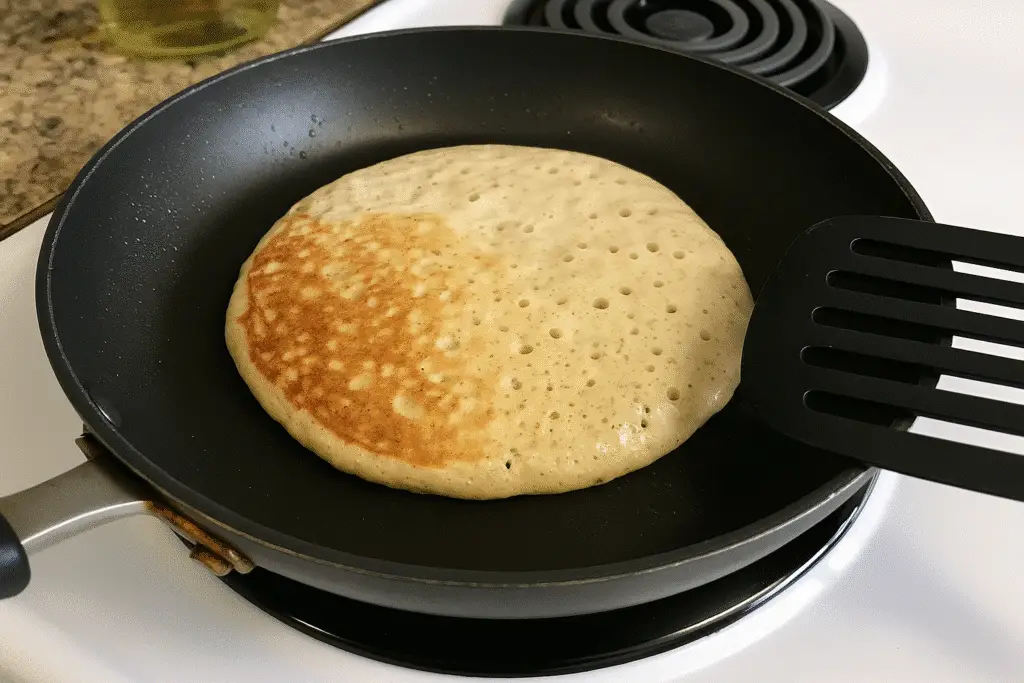 Cooking cottage cheese protein pancakes in non-stick pan showing golden brown color