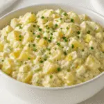 Hellmann's potato salad recipe in white bowl with creamy mayo dressing and fresh herbs