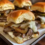 Philly cheesesteak sliders with melted provolone cheese and caramelized grilled onions on Hawaiian rolls